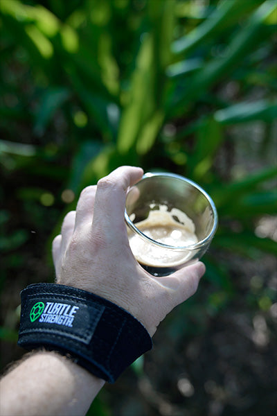 Hand holding coffee with lifting strap around wrist